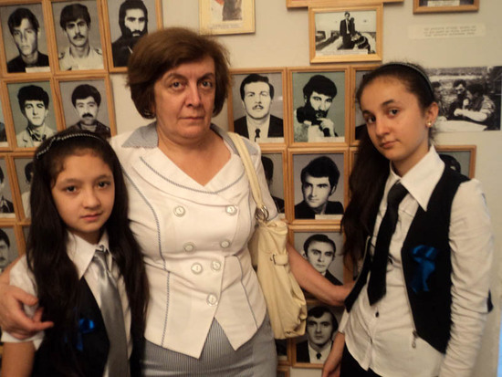 Вера Герасимовна с девочками рядом с фотографией погибшего сына своей подруги.