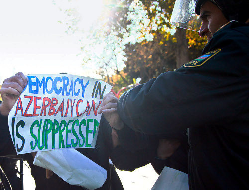 Полицейский пытается отобрать у демонстранта плакат с надписью: "В Азербайджане подавляется демократия". Баку, 2012 г. Фото Азиза Каримова для "Кавказского узла"