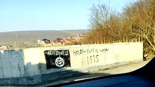 Изображение флага, используемого боевиками «Исламского государства» (признанного 29 декабря 2014 г. Верховным судом России террористической организацией), на стене в селении Хосе-Юрте. Фото: Стоп-кадр видео ИГИШ в Хоси -Юрте / IG in Chechnya, http://www.youtube.com/watch?v=n2sVCqLfPp0