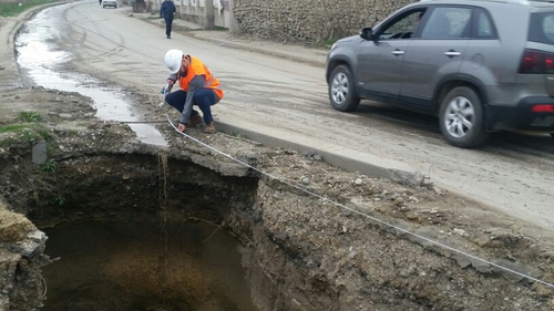 Активист ОНФ замеряет яму на ул. Крылова в Махачкале