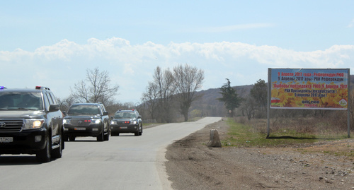 Машины с правительственными номерами Южной Осетии на фоне агитационного плаката. 8 апреля 2017 года. Фото Алана Цхурбаева для "Кавказского узла".