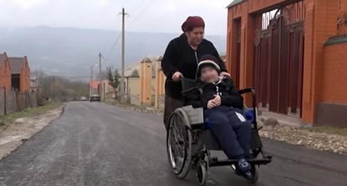 10-летний инвалид-колясочник на асфальтированной дороге в Бетти-Мохке. Фото: Стоп-кадр видео  https://www.youtube.com/watch?time_continue=25&v=Pbs4s44JVUk