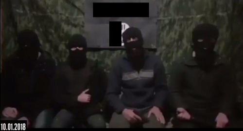 Четверо людей в масках на фоне флага "Исламского государства"* обратились с призывом убивать российских правозащитников. Фото: скриншот видео. 