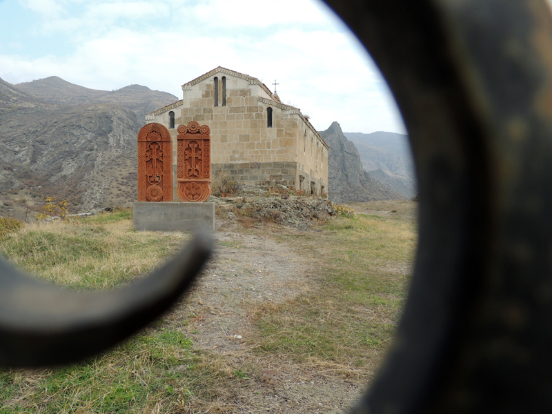Раннехристианский монастырь Цицернаванк. Вид через ограду. Во дворе монастыря видны два современных хачкара.