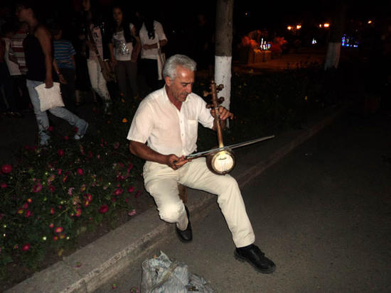 Вечером на площади. Мужчина играет на кеманче народные армянские мелодии.