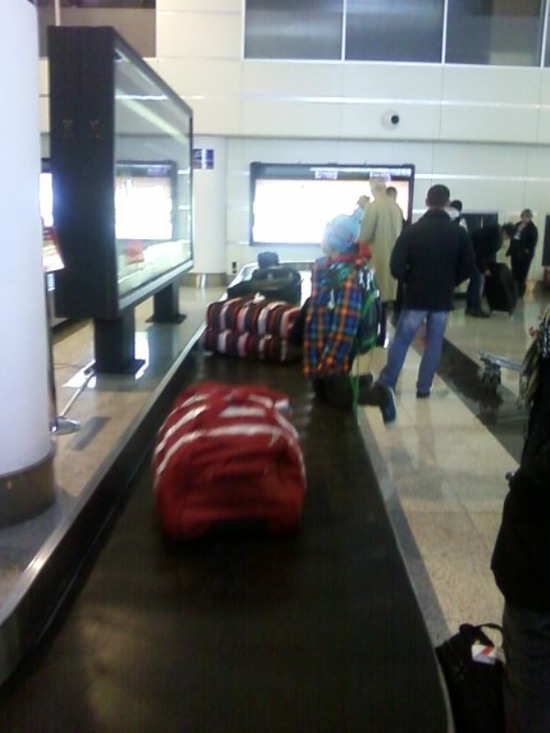 Ожидая своего чемаданчика, пацан катается на ленте доставки багажа. Тбилиси.