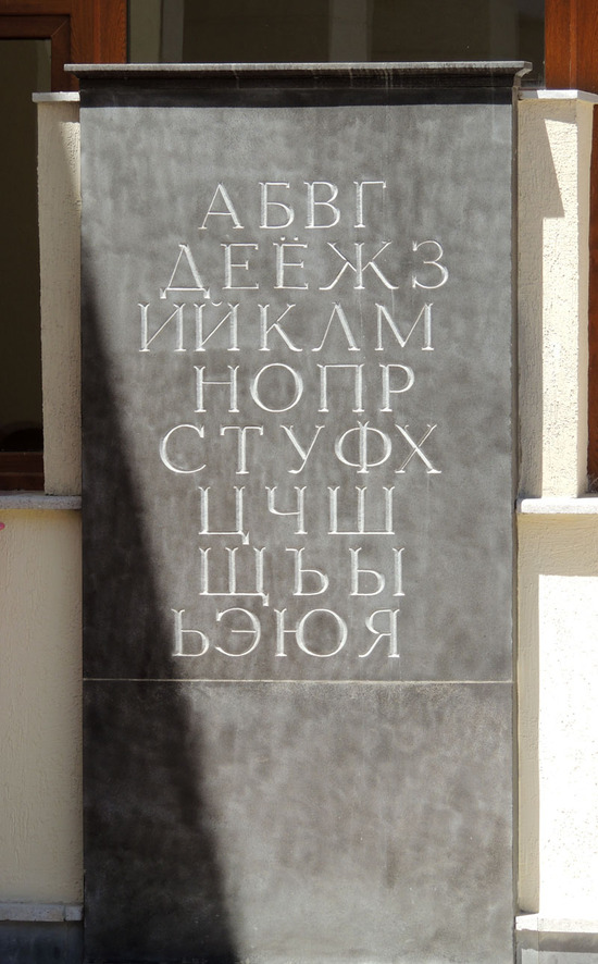 Алфавит на каменной плите в школьном дворе.