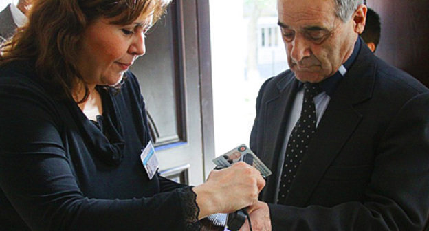 На 5-ом избирательном участке Насиминского района Баку член избиркома проверяет специальным прибором наличие невидимых чернил на пальце избирателя. Азербайджан, 7 ноября 2010 года. Турхан Каримов специально для "Кавказского узла"