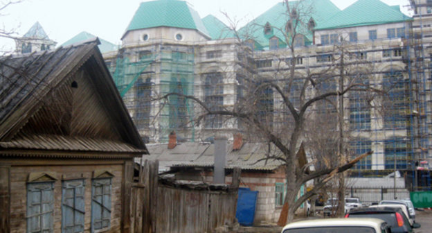 Астрахань. Строящееся здание нового театра рядом с ветхими деревянными домами. 17 марта 2011 г. Фото "Кавказского узла"
