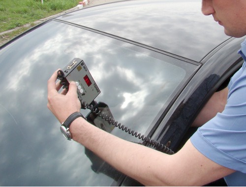 Сотрудник ГИБДД измеряет уровень светопропускания стекол автомобиля. Фото: www.gibddnso.ru