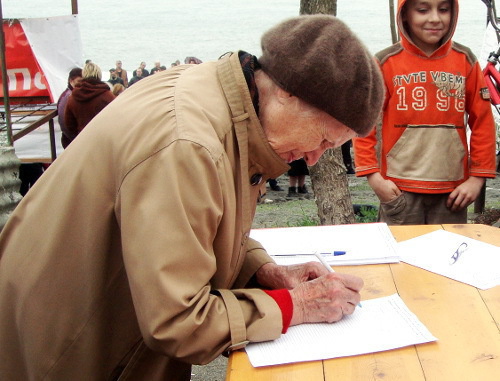 Жительница Сочи подписывает резолюцию митинга в защиту естественных пляжей и парковых зон Имеретинской низменности от коммерческих застроек. Сочи, 10 апреля 2012 г. Фото Светланы Берестеневой для "Кавказского узла"