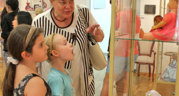 Благотворительная выставка в помощь детям, больным онкологией и выставка "Родом из детства" открылась в  музее изобразительных искусств. На снимке: бабушка показывает своим внучкам какая кукла была у нее в детстве. Ростов-на-Дону, 1 июня 2012. Фото Олеси Диановой для "Кавказского узла"