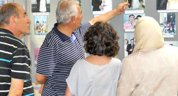 Выставка ко Дню репатрианта проходит в Майкопе. На снимке: участники выставки рассматривают фотографии. Адыгея, Майкоп, 30 июля 2012 г. Фото Олега Чалого для "Кавказского узла"