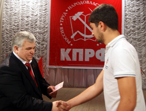 Первый секретарь Северо-Осетинского Рескома КПРФ Казбек Тайсаев вручает партийные и комсомольские билеты новым членам КПРФ и ЛКСМ во время торжетсвенного собрания в честь Дня Октябрьской революции. Владикавказ, 7 ноября 2012 г. Фото: Сайт Северо-Осетинского республиканского отделения КПРФ, http://www.rso-kprf.ru