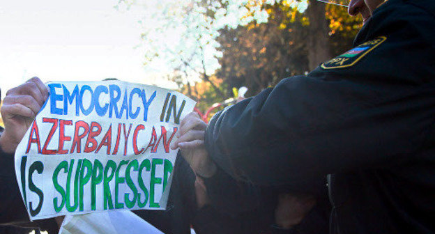 Полицейский пытается отобрать у демонстранта плакат с надписью: "В Азербайджане подавляется демократия". Баку, 2012 г. Фото Азиза Каримова для "Кавказского узла"