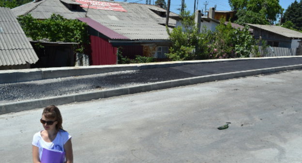 В центре - дом 5-а по улице Акаций. На переднем плане - жительница дома Юлия Салтыкова на строящемся участке федеральной дороги, вплотную прилегающем к жилью. Сочи, 2 июня 2013 г. Фото Светланы Кравченко для "Кавказского узла"