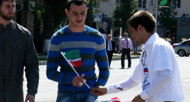 Представитель партии "Единая Россия" раздает флажки с триколором чеченского флага на праздновании Дня республики. Чечня, Грозный, 6 сентября 2012 г. Фото: chechen.er.ru