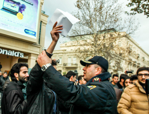 Баку, Площадь фонтанов, 8 декабря 2013 г. Полицейский препятствует проведению безмолвной акции против повышения цен на топливо. Фото Азиза Каримова для "Кавказского узла"