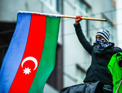 Участник митинга против повышения цен на топливо, организованный НСДС, держит флаг Азербайджана. Баку, 15 декабря 2013 г. Фото Азиза Каримова для «Кавказского узла»