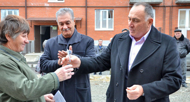 Глава администрации местного самоуправления  Алагирского района Руслан Хадарцев ( на фото справа) вручает ключи от новой квартиры Симе Качмазовой, в центре - заместитель главы  администрации местного самоуправления  Алагирского района Алагирского района Олег Токаев. Северная Осетия, Алагир, 18 ноября 2014 г. Фото Дмитрия Тамерланова для "Кавказского узла"