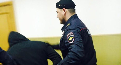 Сотрудник полиции конвоирует подозреваемого по делу Б.Немцова. Басманный суд г. Москвы, 6 апреля 2015 года. 