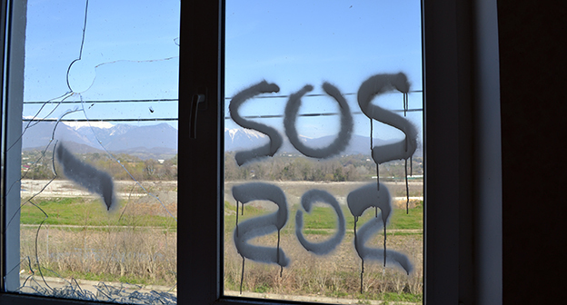 Надпись SOS на стекле разоренного коттеджа в поселке для переселенцев олимпиады "Веселое-Псоу" на границе с Абхазией. Фото Светланы Кравченко для "Кавказского узла"