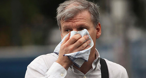 Мужчина прячет лицо от удушливого запаха. Волгоград.  Фото: http://gorodskoyportal.ru/volgograd/news/society/8363183/