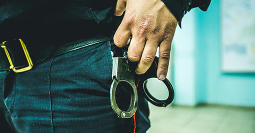 Сотрудник правоохранительных органов с наручниками. Фото: Денис Яковлев / Югополис