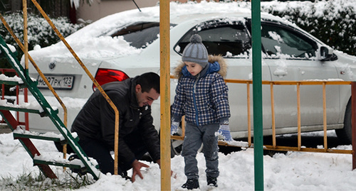 Отец лепит снеговика во дворе дома в Сочи. Фото Светланы Кравченко для Кавказского узла"