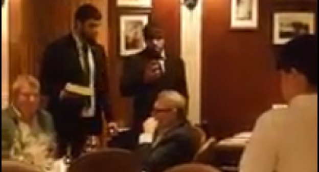Двое напавших на Михаила Касьянова с тортом стоят возле политика в зале ресторана в Москве. Скриншот видеозаписи нападения с сайта tv.mk.ru.