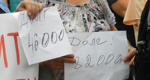 Бумажные листы с суммами долга в руках рабочих. Фото Татьяны Филимоновой для "Кавказского узла"