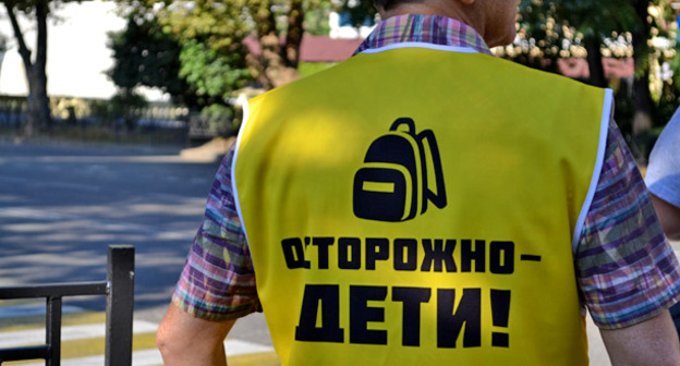 Сотрудник школы № 8 помогает детям переходить на другую сторону улицы. Сочи, 1 сентября 2016 г. Фото Светланы Кравченко для "Кавказского узла"