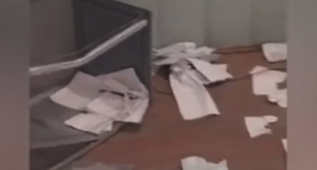 Перевернутая урна для голосования и разбросанные бюллетени на участке в Гоцатле. Скриншот видеозаписи из группы "Дагестан online" в Facebook, facebook.com/groups/dagonline