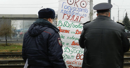 Сотрудники полиции читают плакат участника пикета. 31 октября 2016 г. Фото Татьяны Филимоновой для "Кавказского узла"