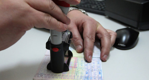 Работник таможенной службы ставит печать в пасморт. Фото: Sputnik/Андрей Александров