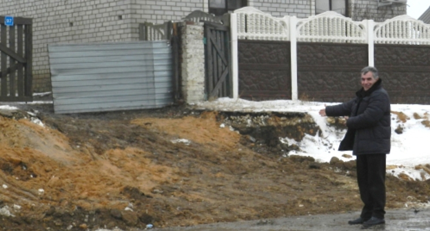 Житель Гумрака показывает, каким стал въезд в его двор в результате реконструкции трассы. Фото Татьяны Филимоновой для "Кавказского узла"