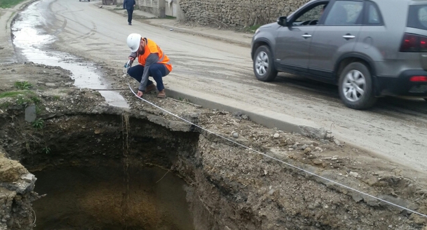 Активист ОНФ замеряет яму на ул. Крылова в Махачкале