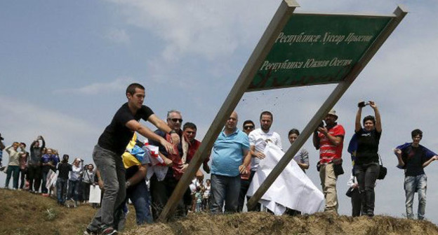 Грузинские журналисты выкорчевывают из земли пограничный знак между Южной Осетией и Грузией.  15 июля 2015 г.  Фото: David Mdzinarishvili/Reuters