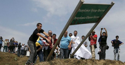 Грузинские журналисты выкорчевывают из земли пограничный знак между Южной Осетией и Грузией.  15 июля 2015 г.  Фото: David Mdzinarishvili/Reuters