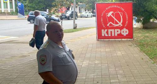 Сотрудник полиции на фоне символики КПРФ. Фото Светланы Кравченко для "Кавказского узла"