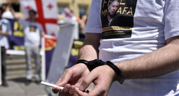 Участник акции в поддержку Эмре Чабука с его портретом. Фото: Mzia Saganelidze (RFE/RL)