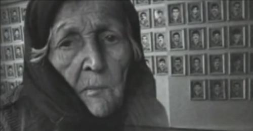 Пожилая женщина на фоне портретов погибших в годы войны и депортации. Фото: скриншот видео youtube канала 
vainakh38