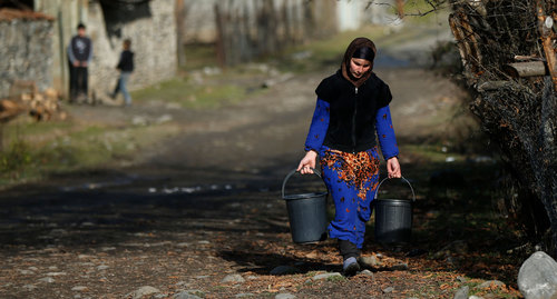Женщина несет ведра с водой на улице в селе Цинубани Панкисского ущелья, Грузия. Фото REUTERS: David MdzinarishviliHEADLINE:A 