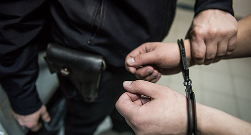 Сотрудник полиции надевает наручники на подозреваемого. Фото: Елена Синеок, Юга.ру