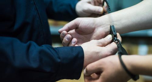 Сотрудник силовых структур надевает наручники. Фото Елены Синеок, Юга.ру