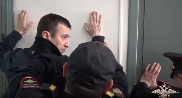 Задержанного Османа Хасбулатова осматривают перед заключением в камеру. Фото: кадр  видео пресс-службы  МВД. https://мвд.рф