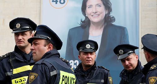 Сотрудники полиции возле плаката с портретом  Саломе Зурабишвили. Фото: REUTERS/David Mdzinarishvili