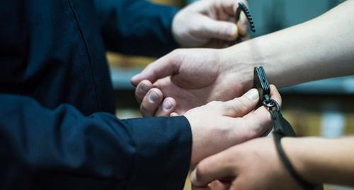 Сотрудник силовой структуры надевает наручники. Фото Елены Синеок, Юга.ру