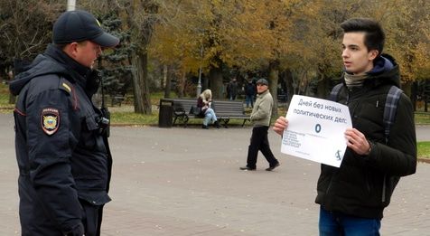 Полицейский рассматривает плакат пикетчика. Пикет привлек внимание прохожего. Волгоград, 17 ноября 2019 года. Фото Татьяны Филимоновой для "Кавказского узла".