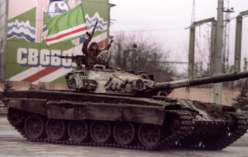 Чеченский танкист машет рукой с вершины захваченного танка, проходя мимо плаката с надписью "За свободу" в центре Грозного, 10 января. Фото Reuters